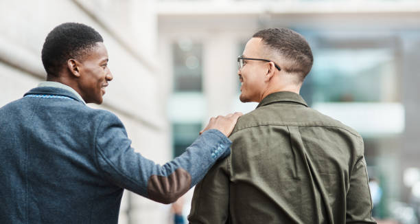 Who says you can’t be personal and professional_ Rearview shot of two young businessmen walking through the city together peer support  stock pictures, royalty-free photos & images