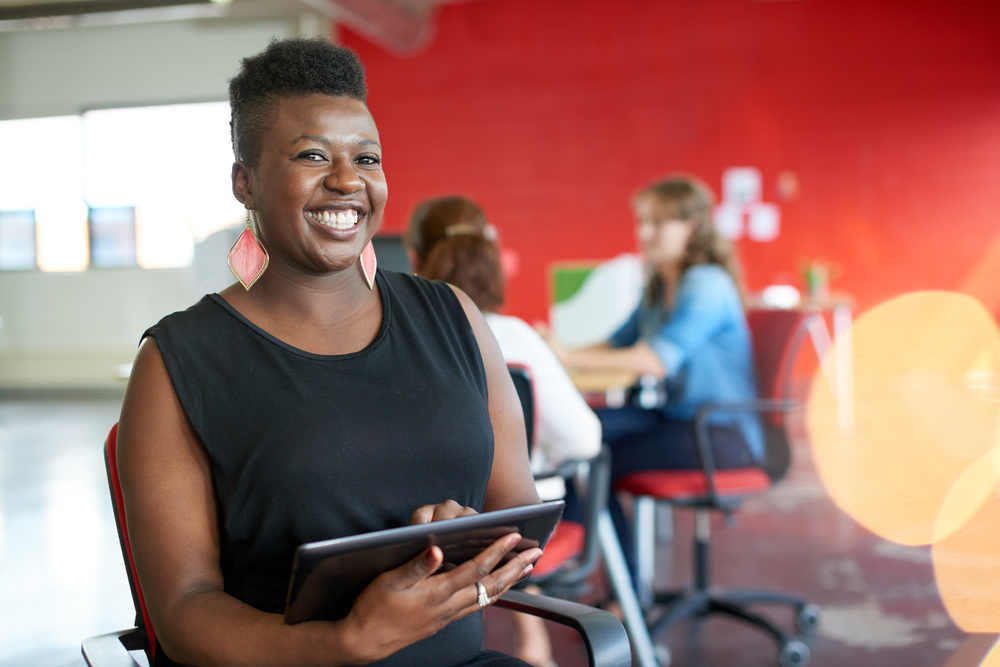 Confident female designer working on a digital tablet in red creative office space